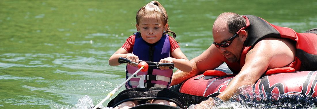 Photo of a little girl and an adult doing water sports at the lake.